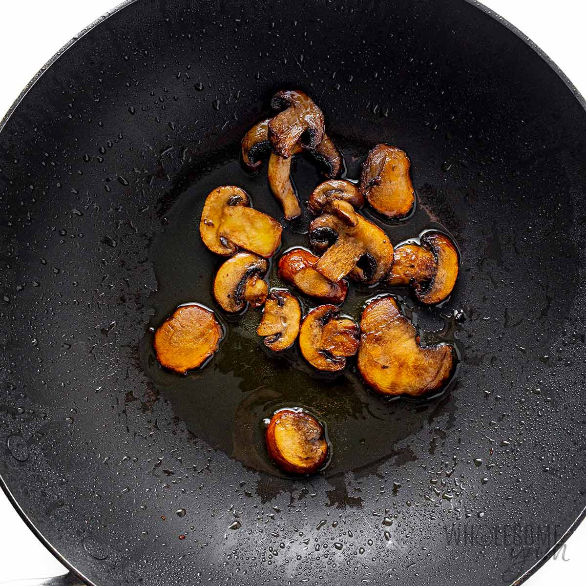 Mushrooms being cooked in a wok.