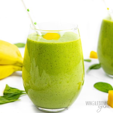 Spinach smoothie in a glass with a straw.