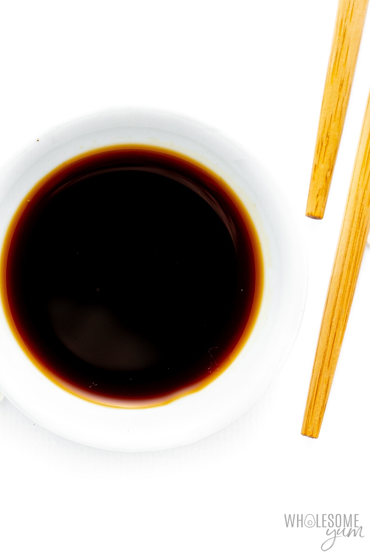 Soy sauce in bowl next to chopsticks.