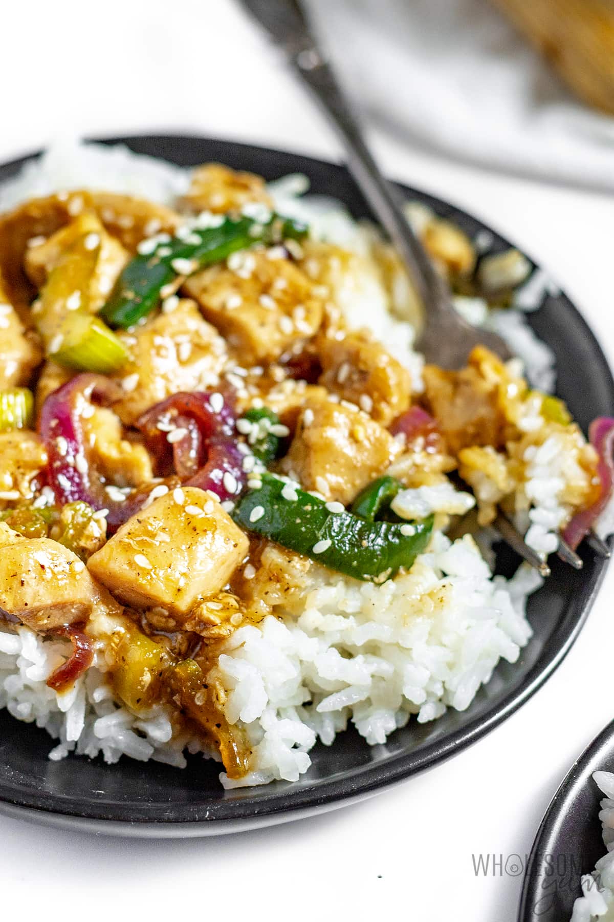Black pepper chicken with rice in a bowl, close up.