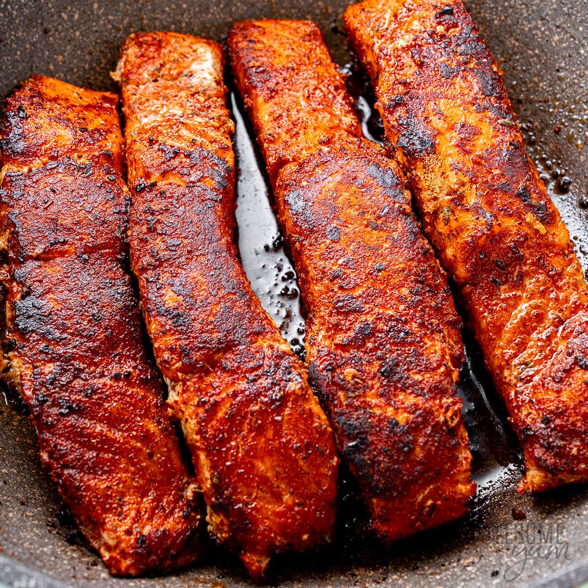 Blackened salmon in a skillet.