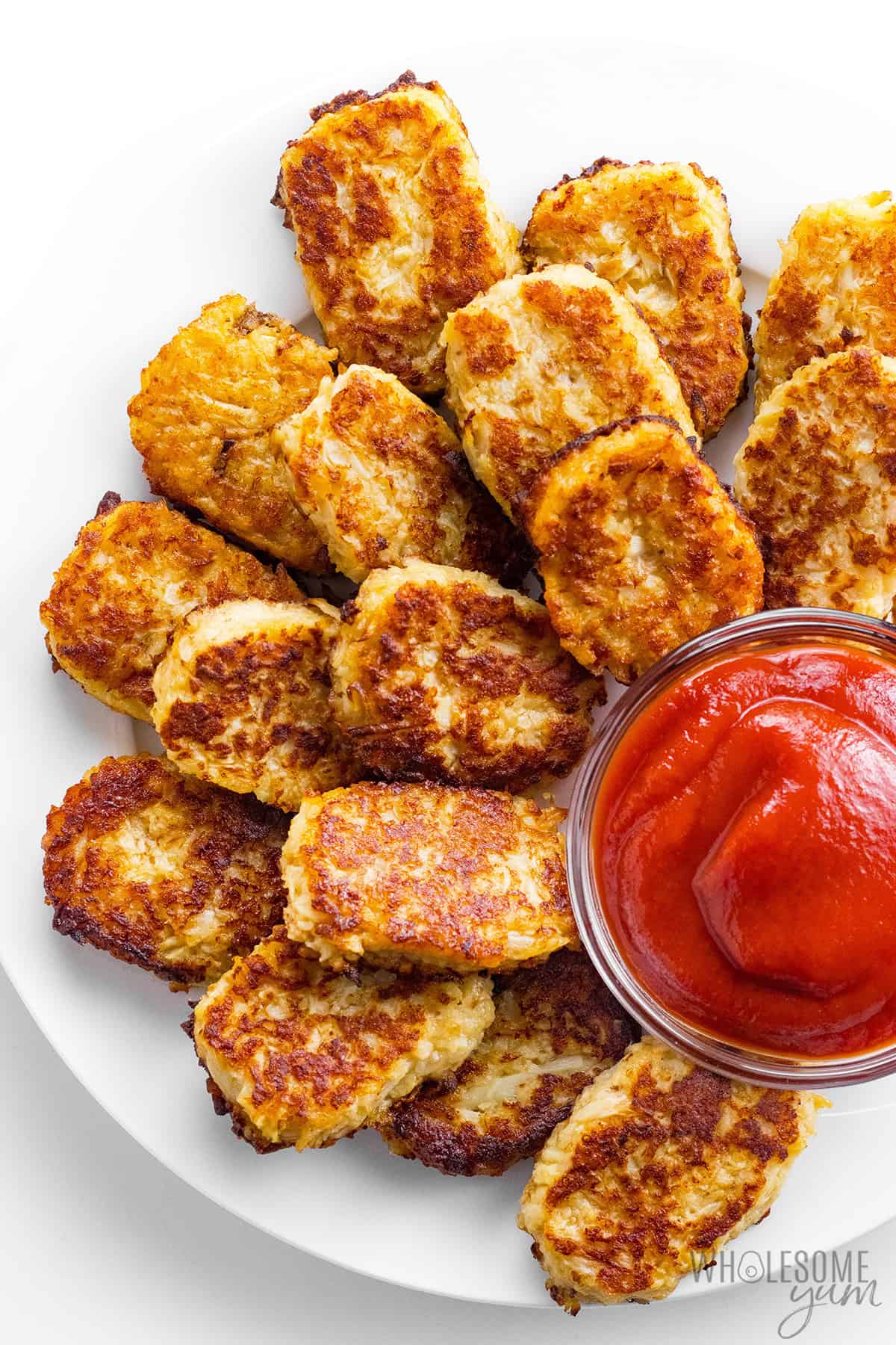 Cauliflower tots on a plate served with ketchup.