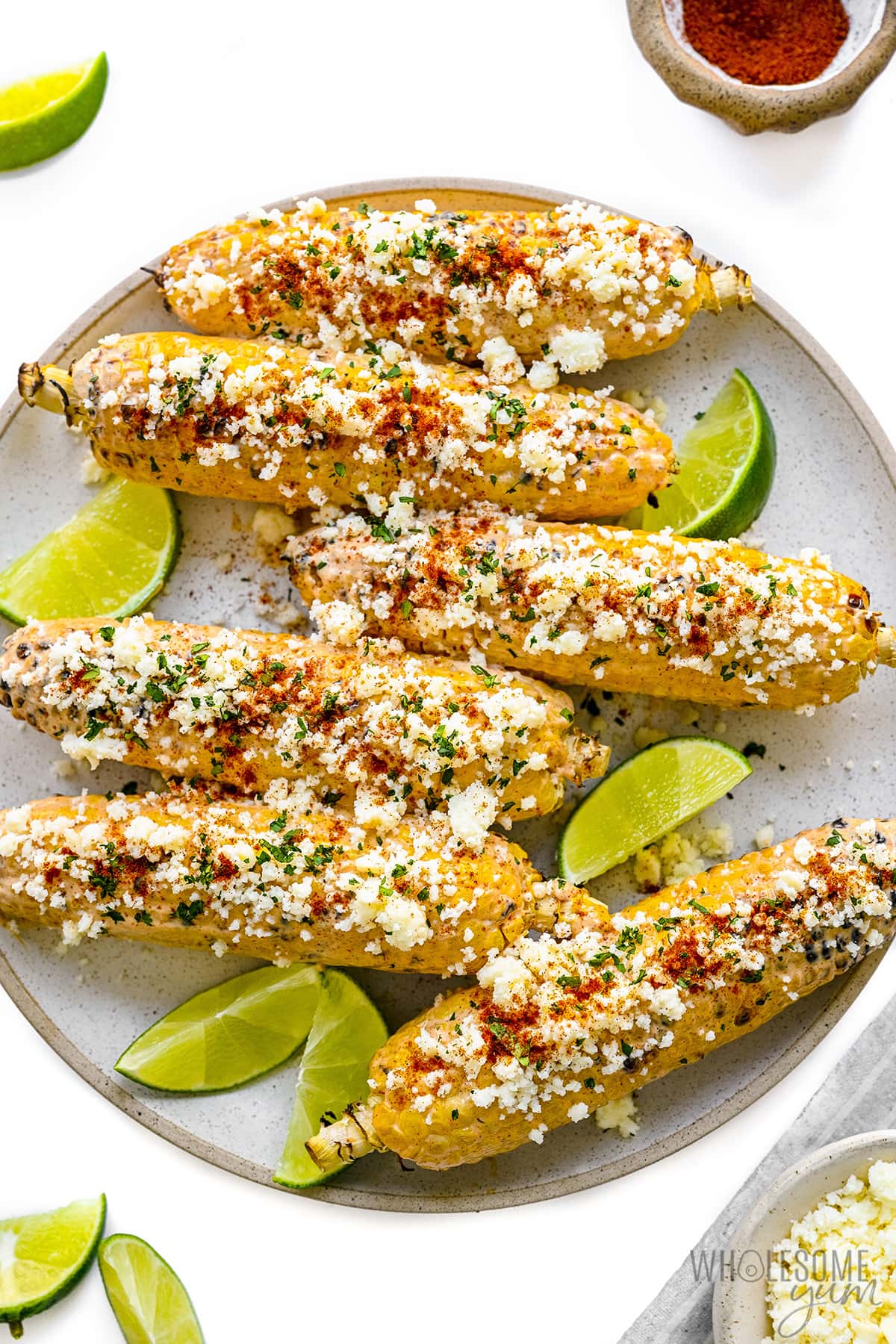 Elote corn on a plate with lime wedges.