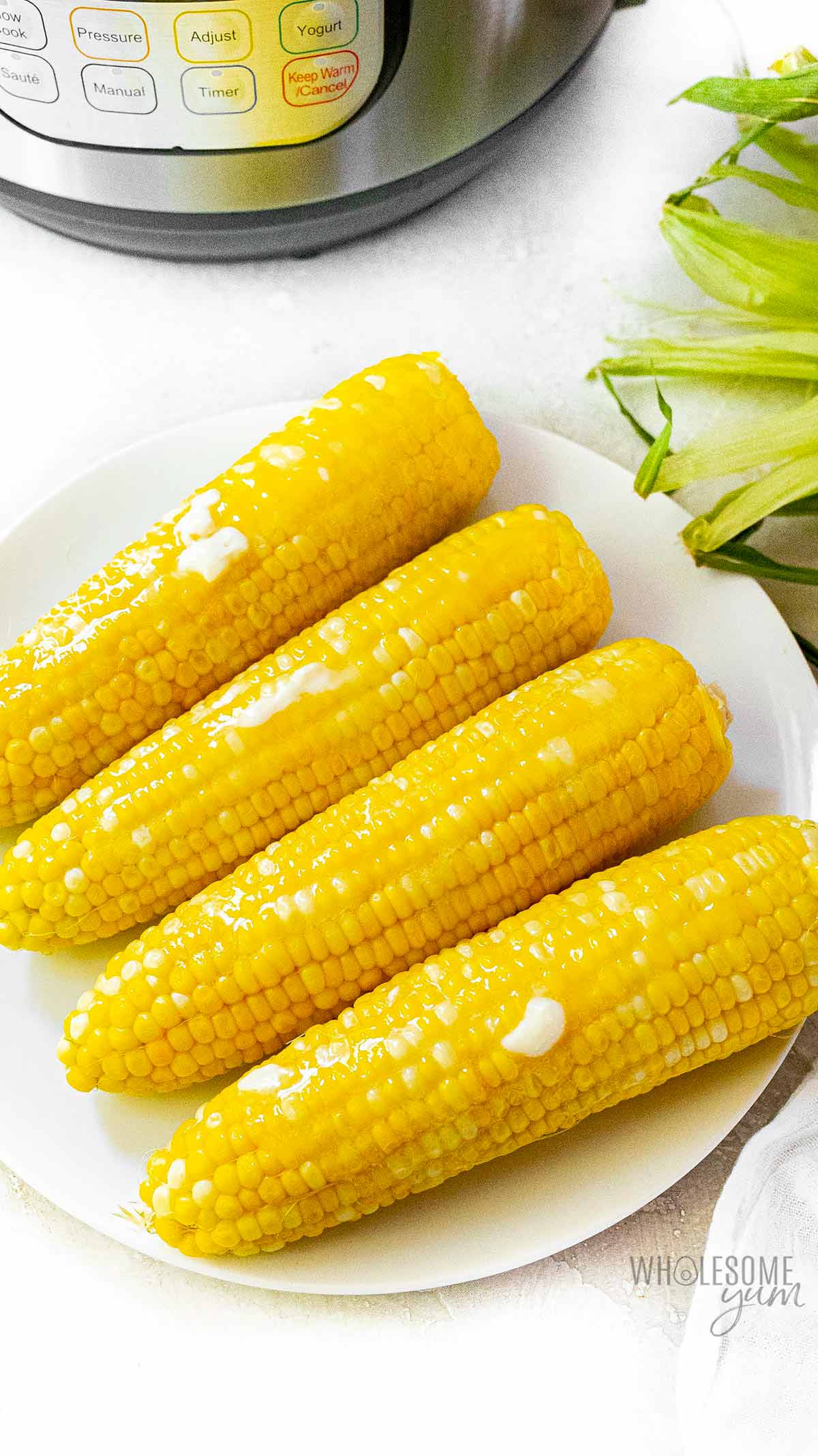 Sliced butter on corn on a plate.