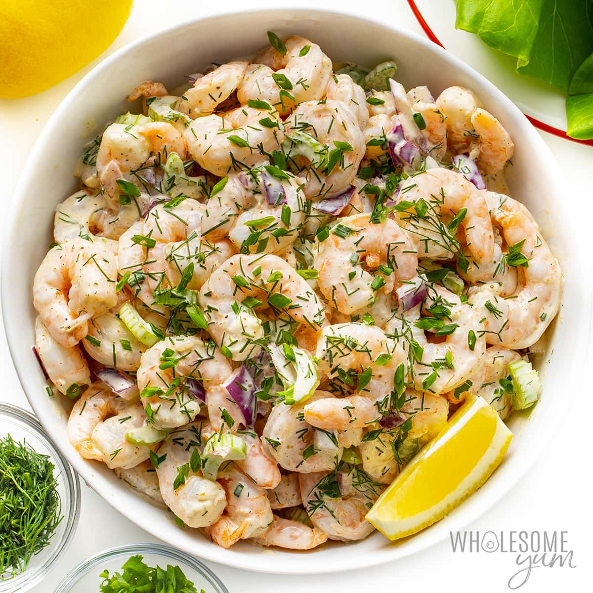 Finished shrimp salad recipe in a bowl with lemon wedge.