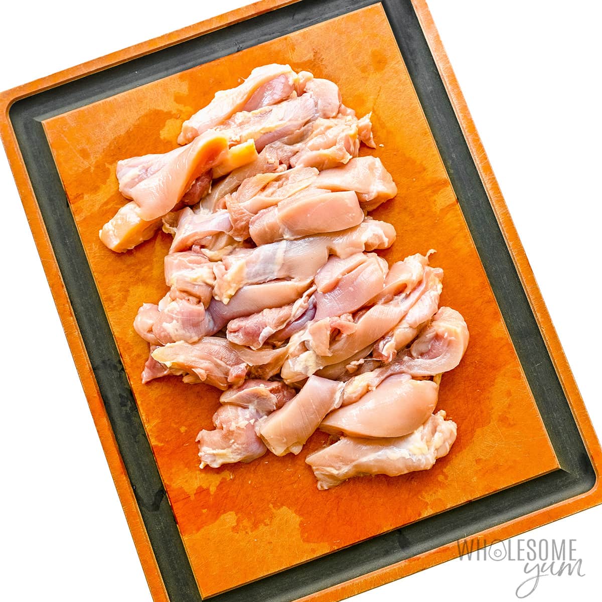 Chicken sliced into strips on a cutting board.