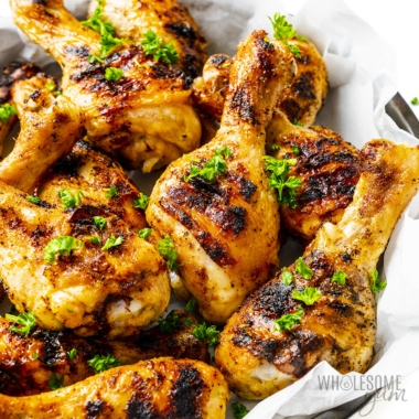 Grilled chicken legs in a bowl up close.