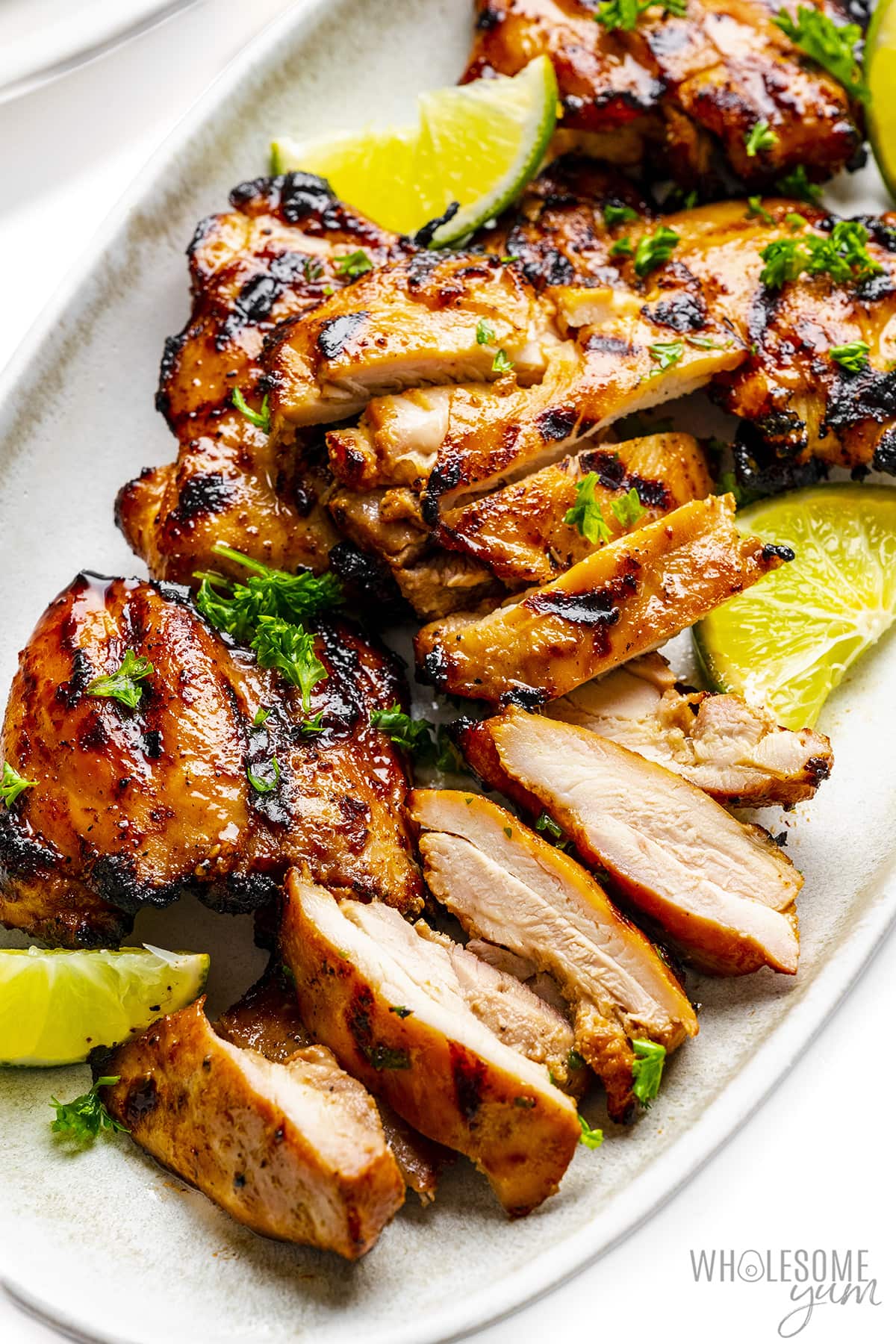 Grilled chicken thighs sliced on a plate.