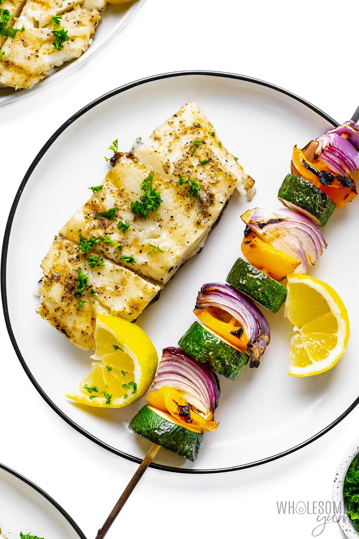 Grilled halibut on a plate with a vegetable skewer.