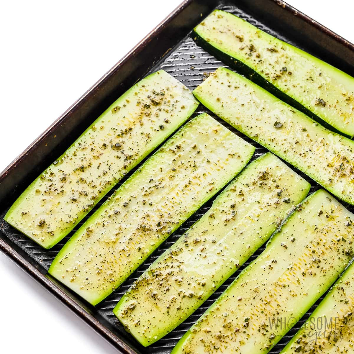 Sliced zucchini seasoned on a sheet pan.