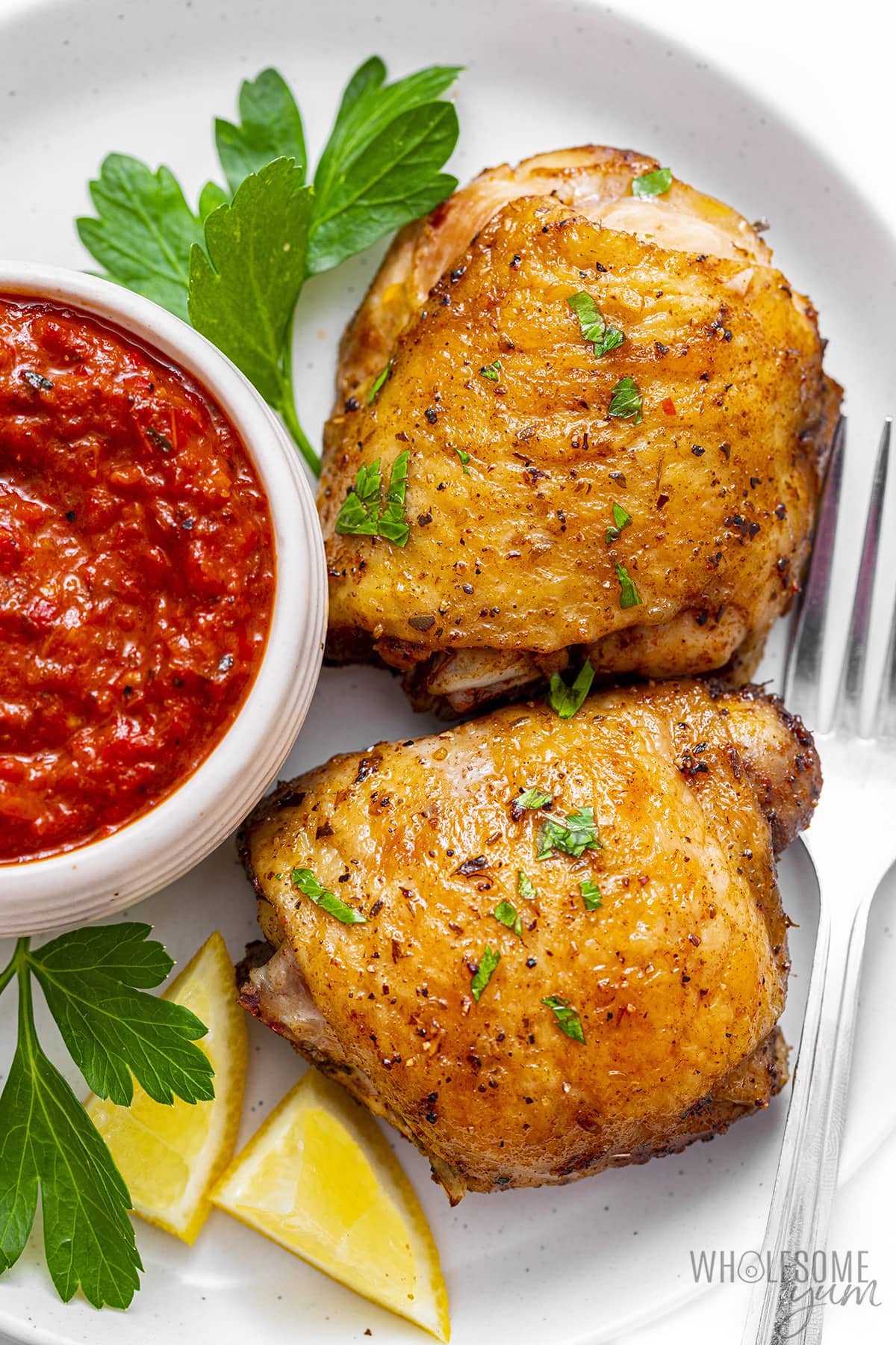 Peri peri chicken on a plate with sauce and a fork.