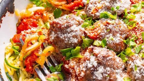 Zucchini spaghetti with meatballs in a bowl with a fork.