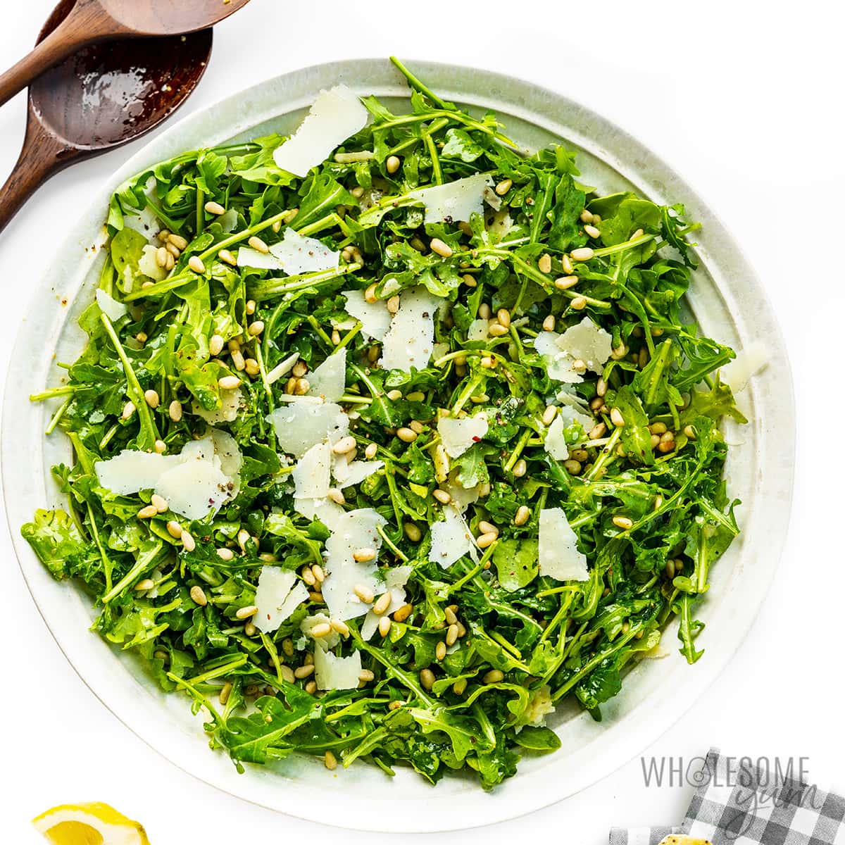 Greens, parmesan, and pine nuts assembled in a bowl.