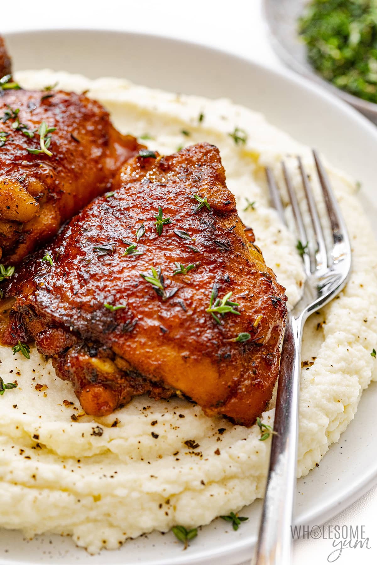 Place the chicken thighs on top of the mashed cauliflower on a plate.