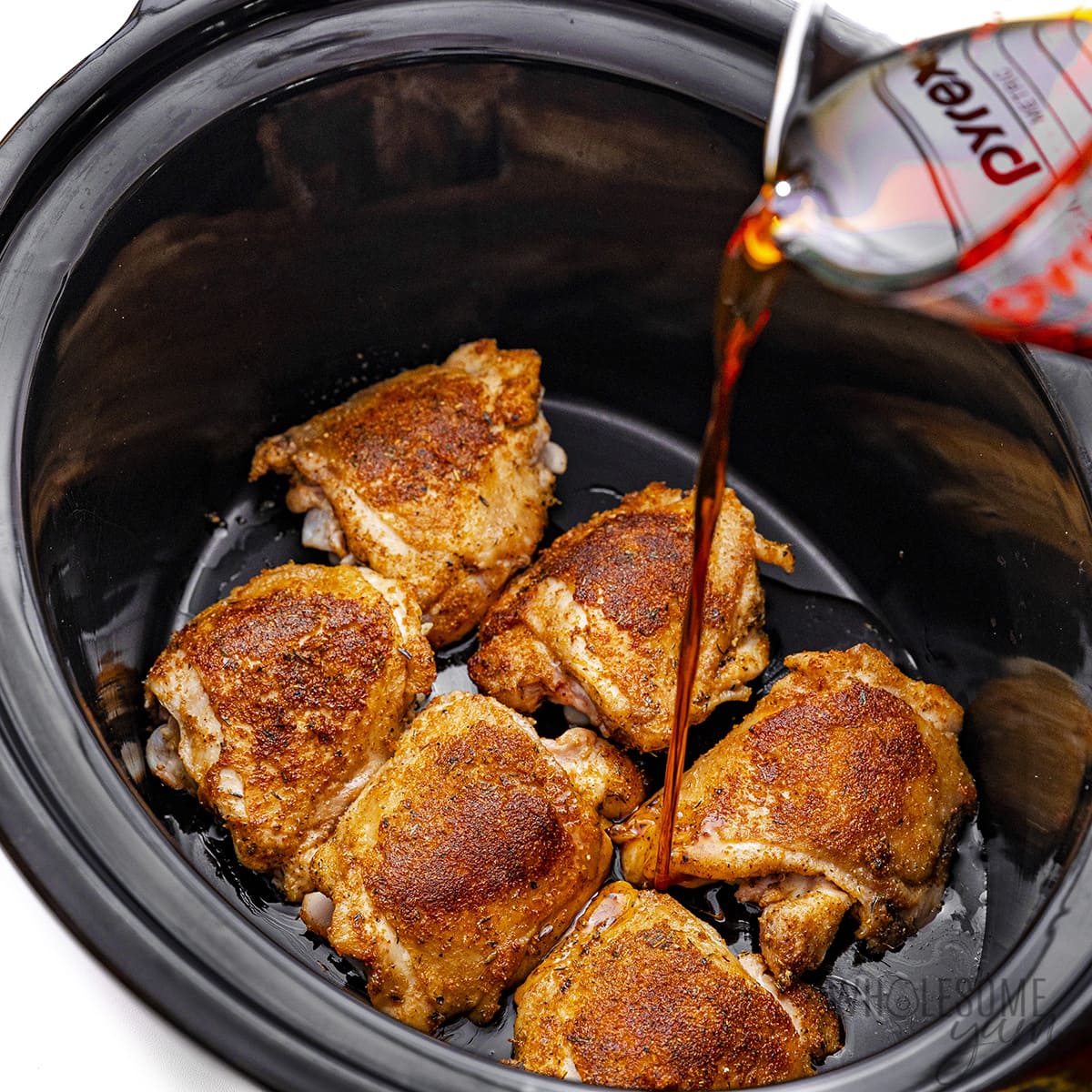 Pour the honey and coconut aminos mixture over the chicken thighs in the pan.