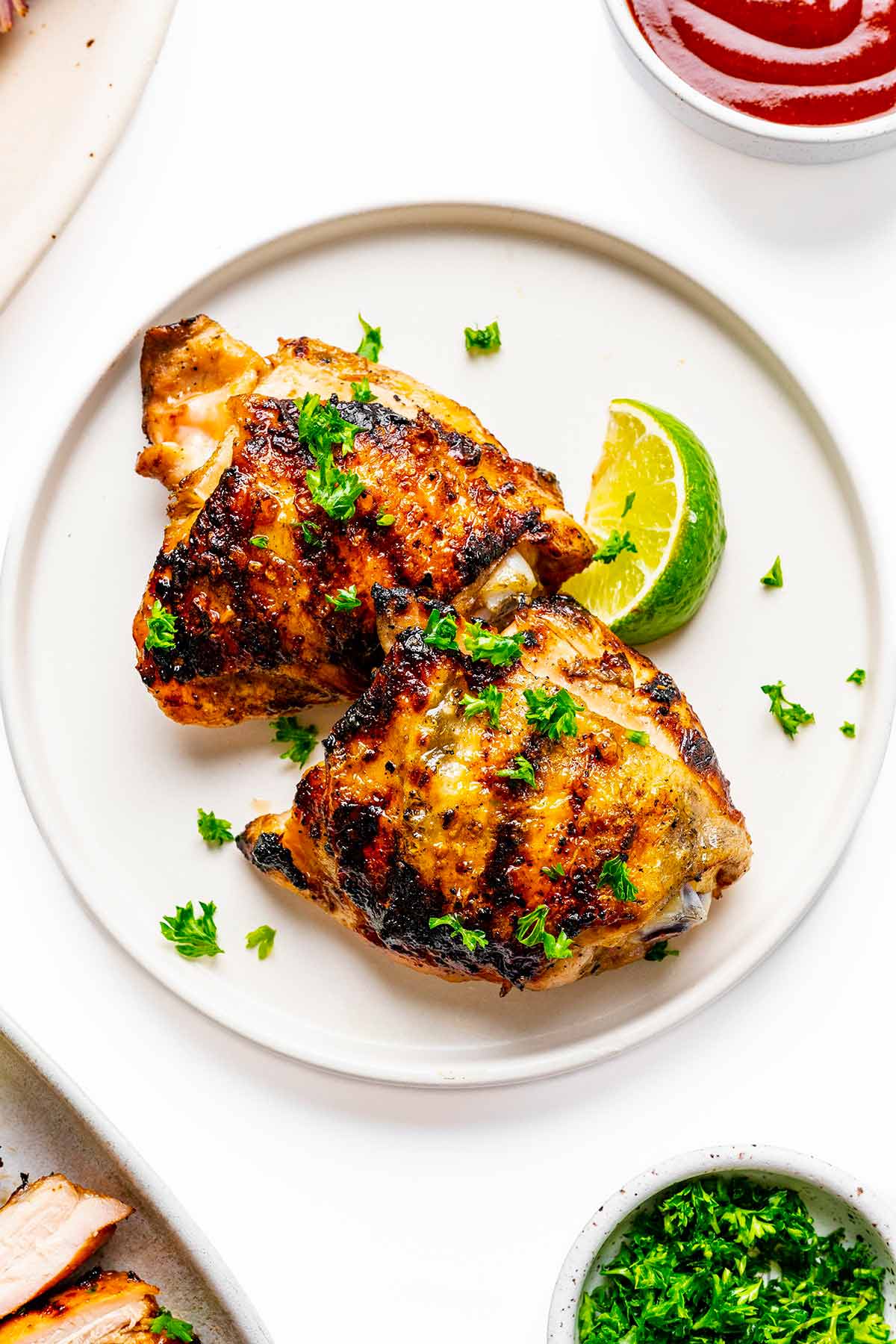 Grilled chicken thighs on a plate with lime wedge.
