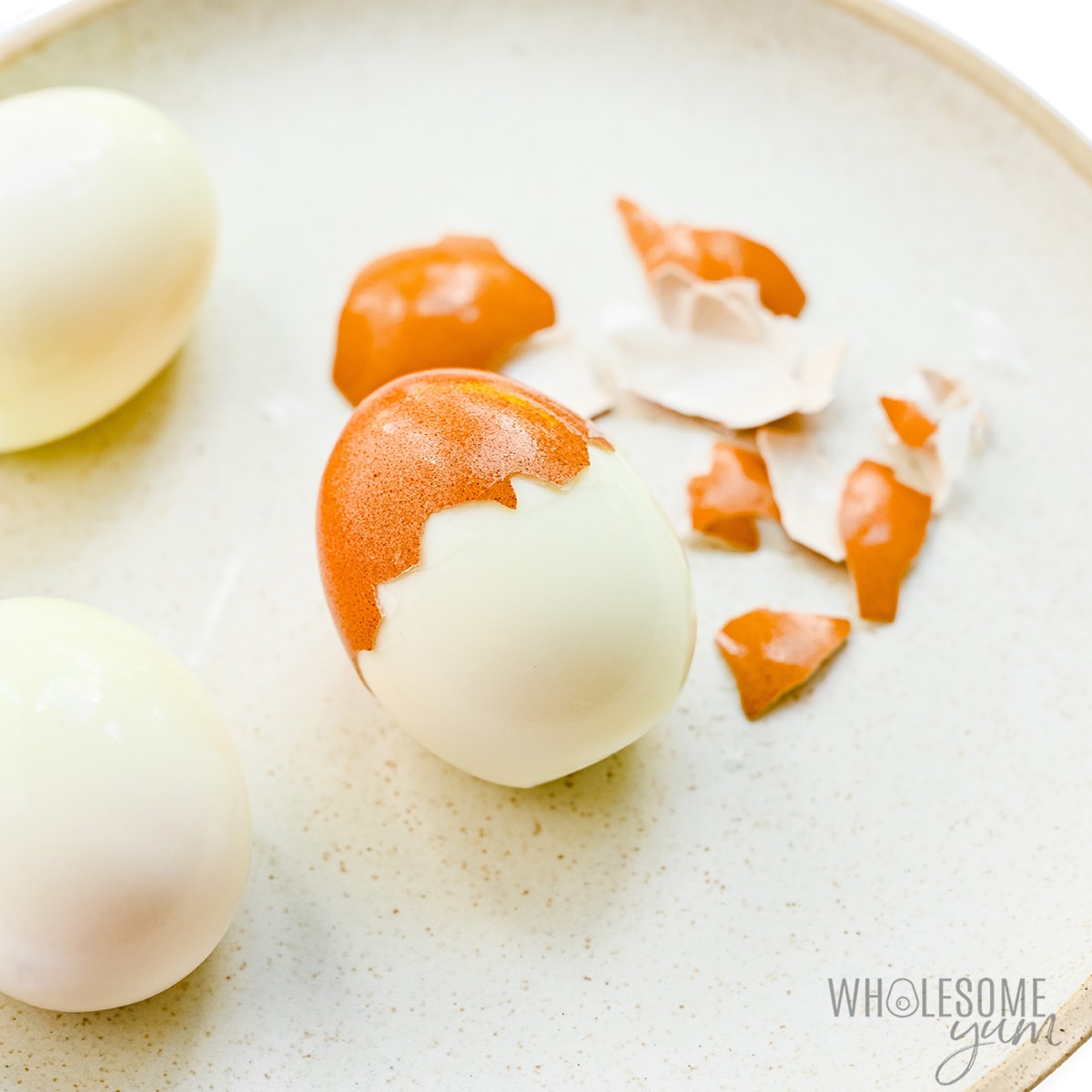 Peeling a soft boiled egg on a plate.