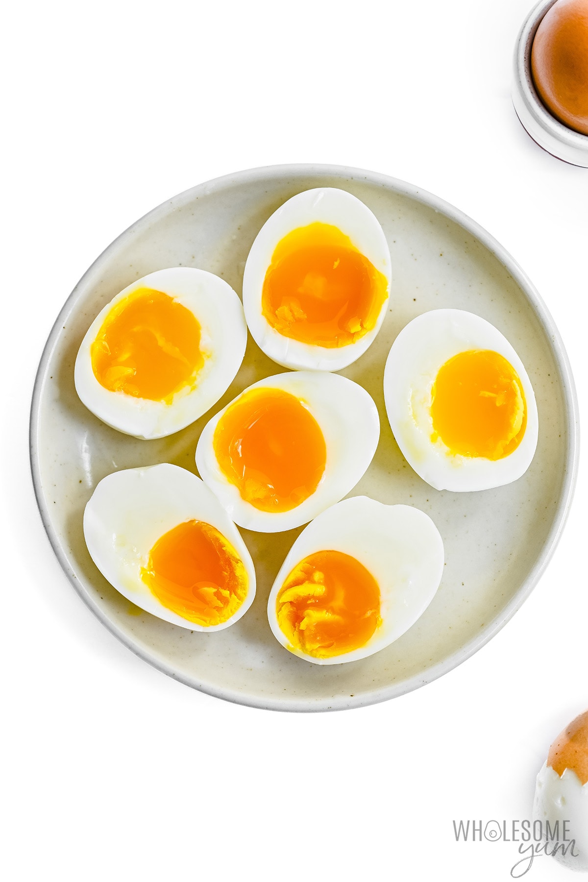Perfect soft-boiled eggs cut in half and served on a plate.