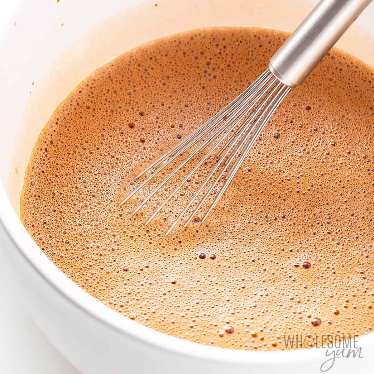 Frothy high protein ice cream base in the bowl with a whisk.