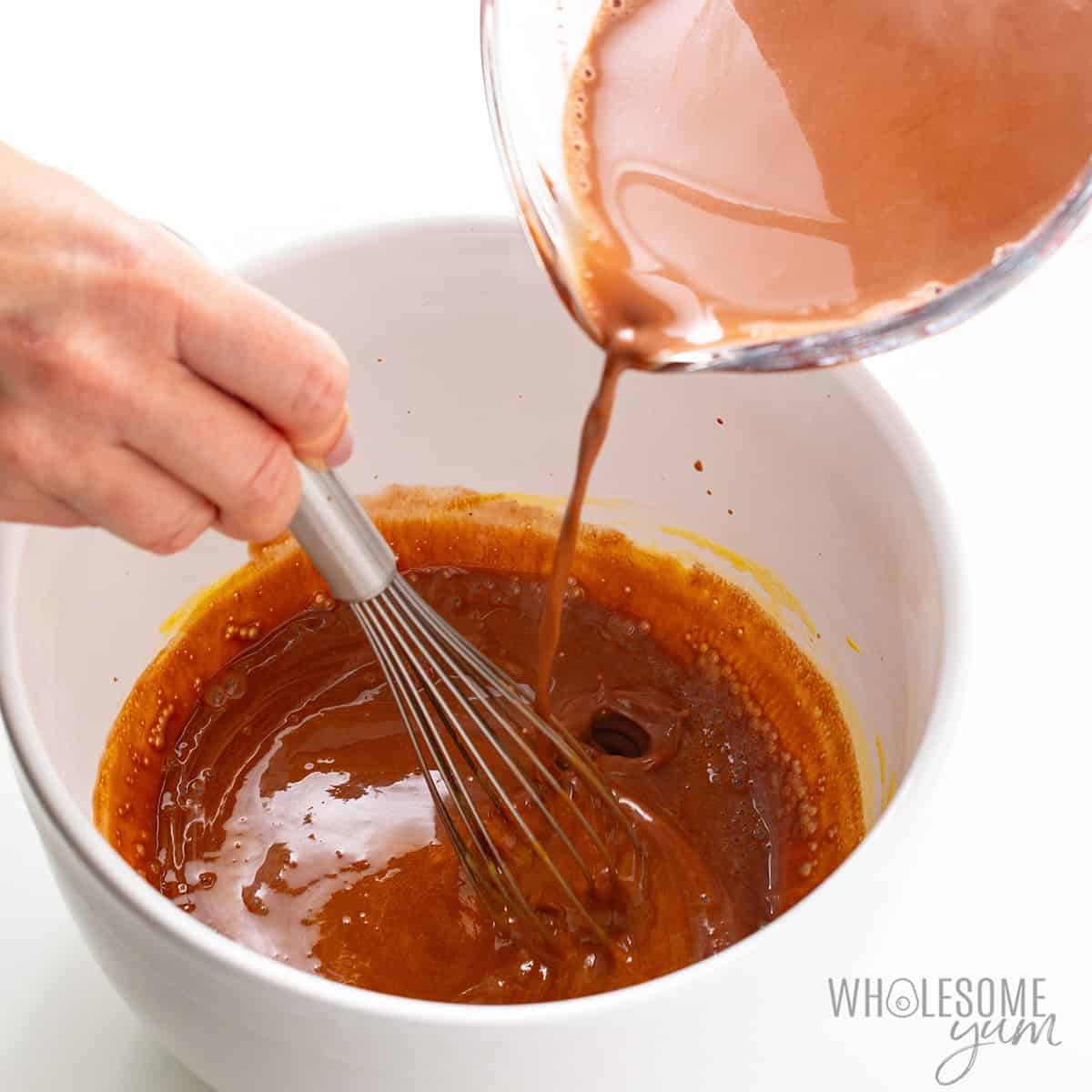 Tempering the egg yolks with the hot cream mixture.