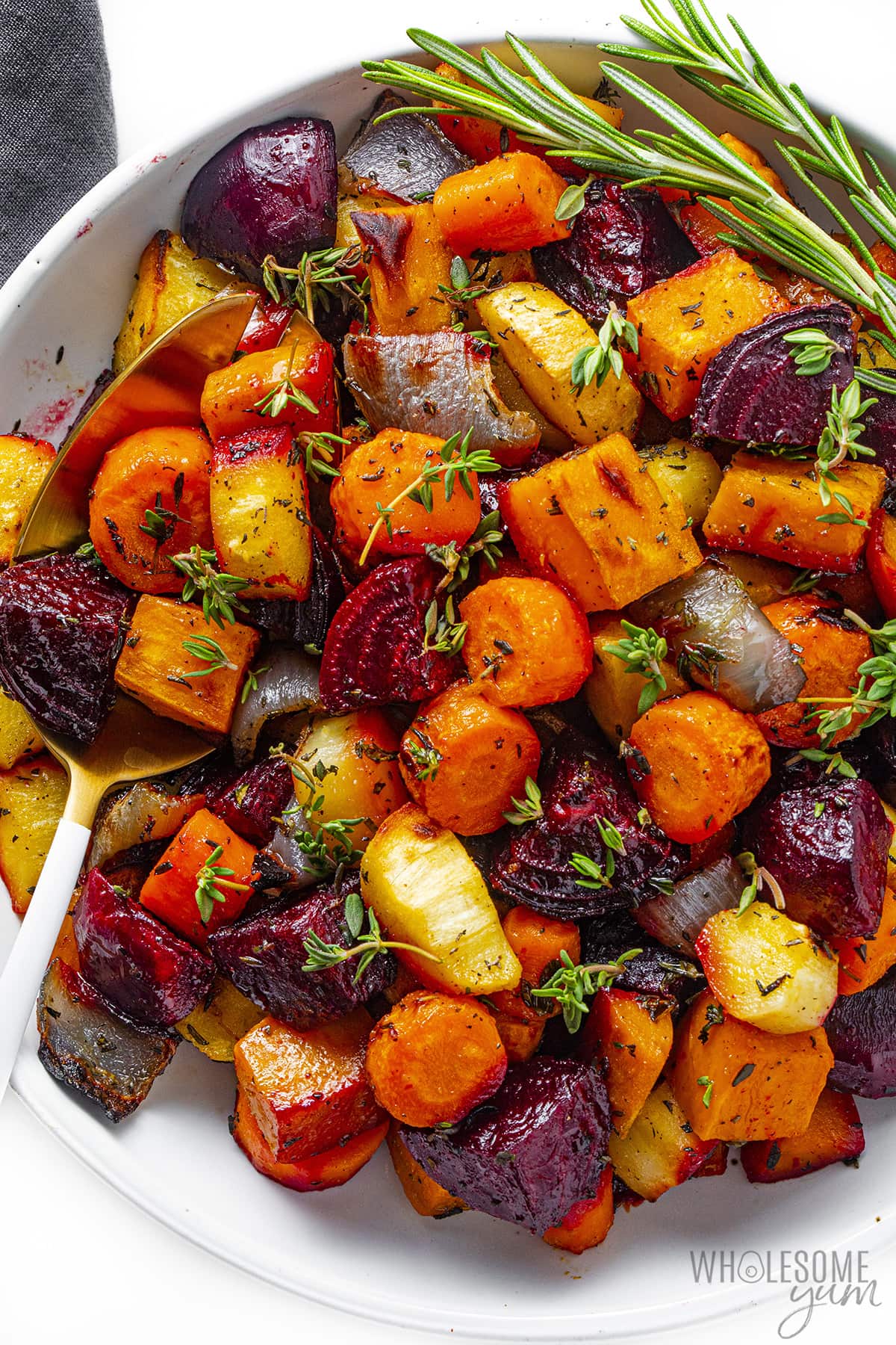 Roasted root vegetables in a bowl with fresh herbs.