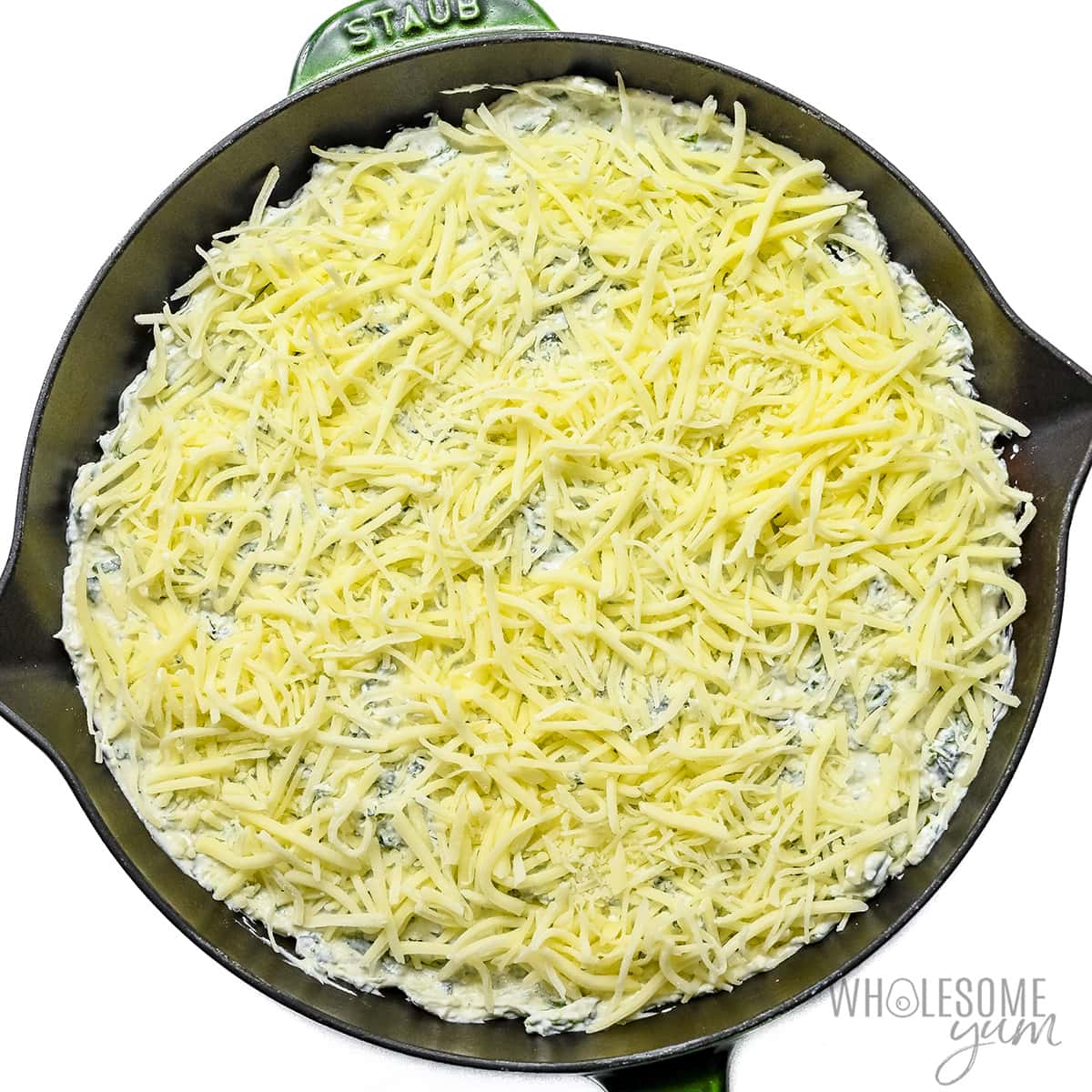Shredded cheese layered on top of spinach mixture.