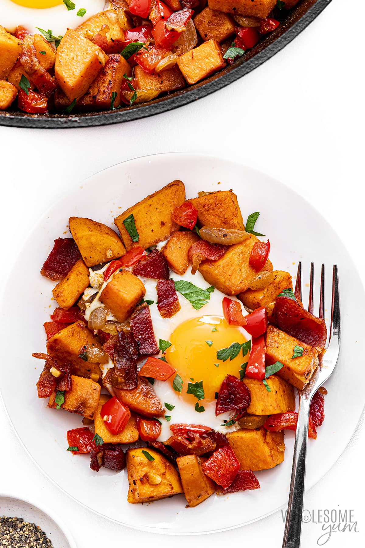 Plate of sweet potato hash next to skillet.