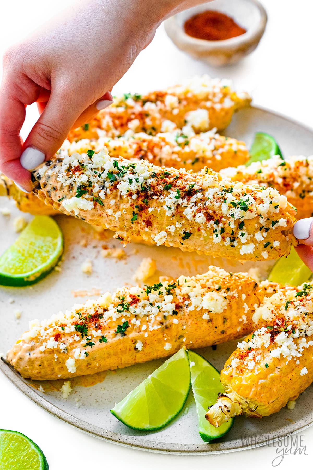 Hands holding up Mexican street corn.