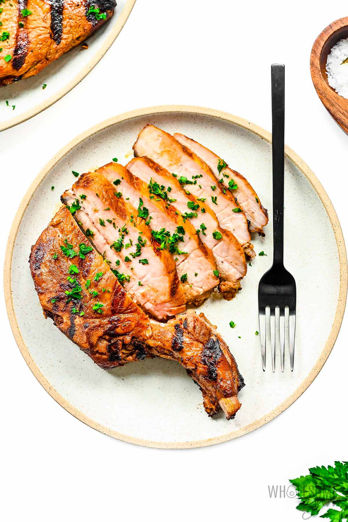 Pork chops sliced on a plate with a fork.