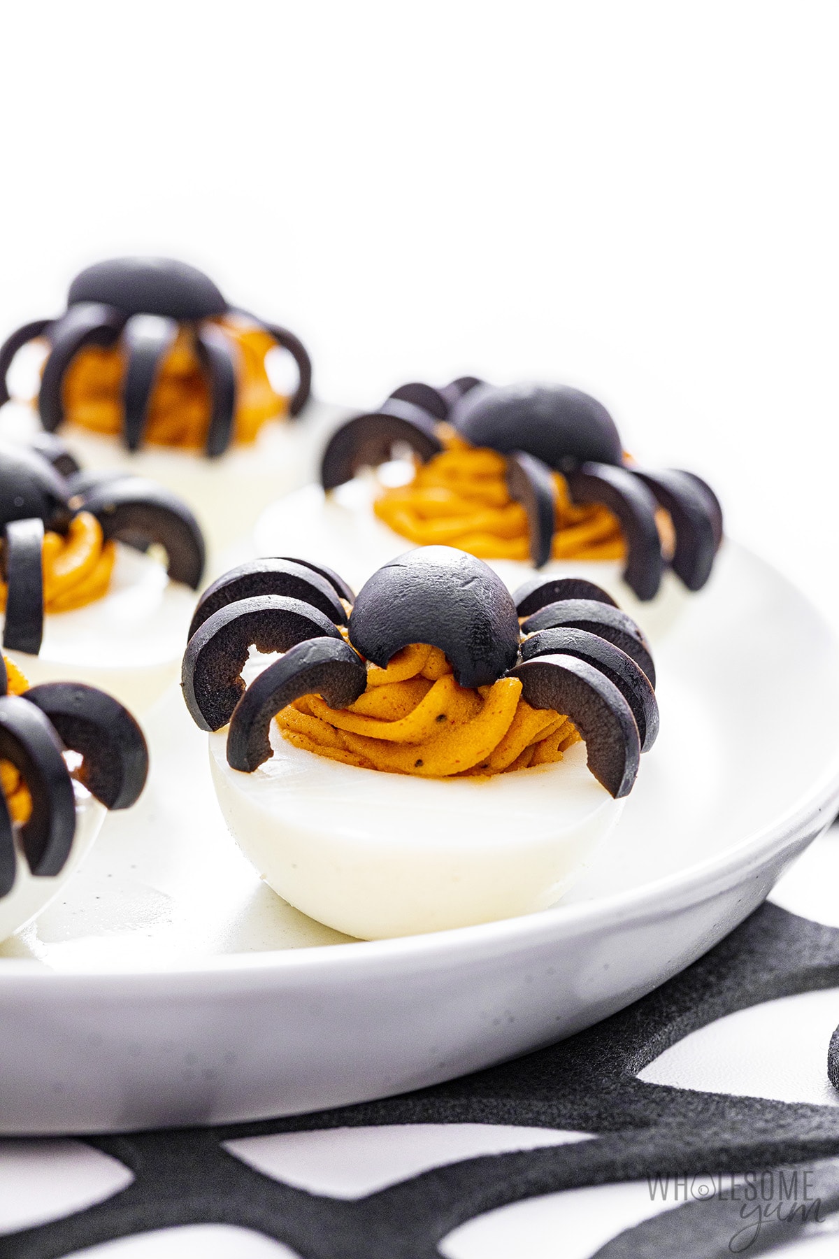 Halloween deviled eggs on plate, side view.