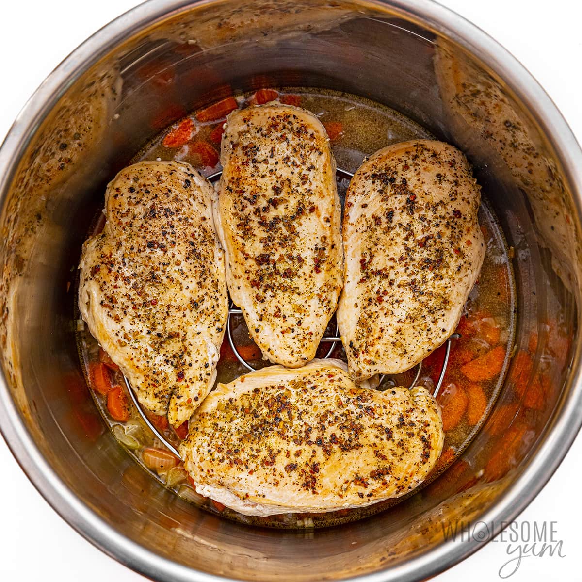 Seasoned chicken placed over rice and veggies in Instant Pot.
