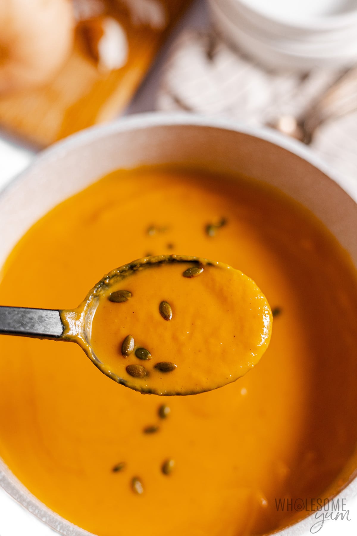 Spoonful of autumn squash soup over a bowl.