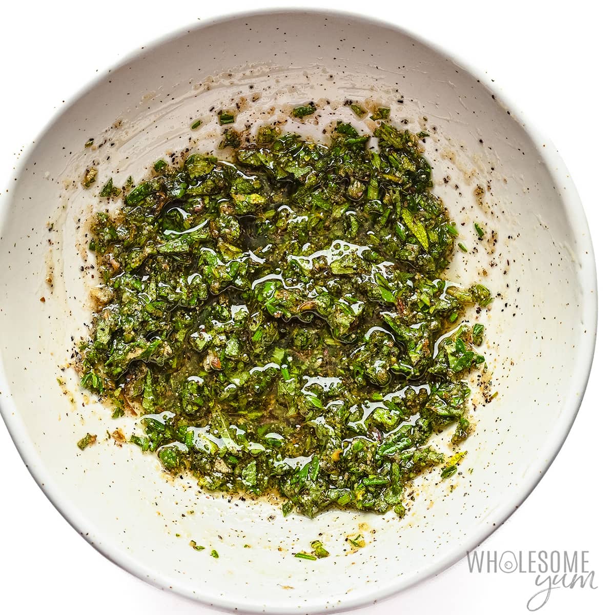Olive oil, herbs, and spices mixed together in a bowl.
