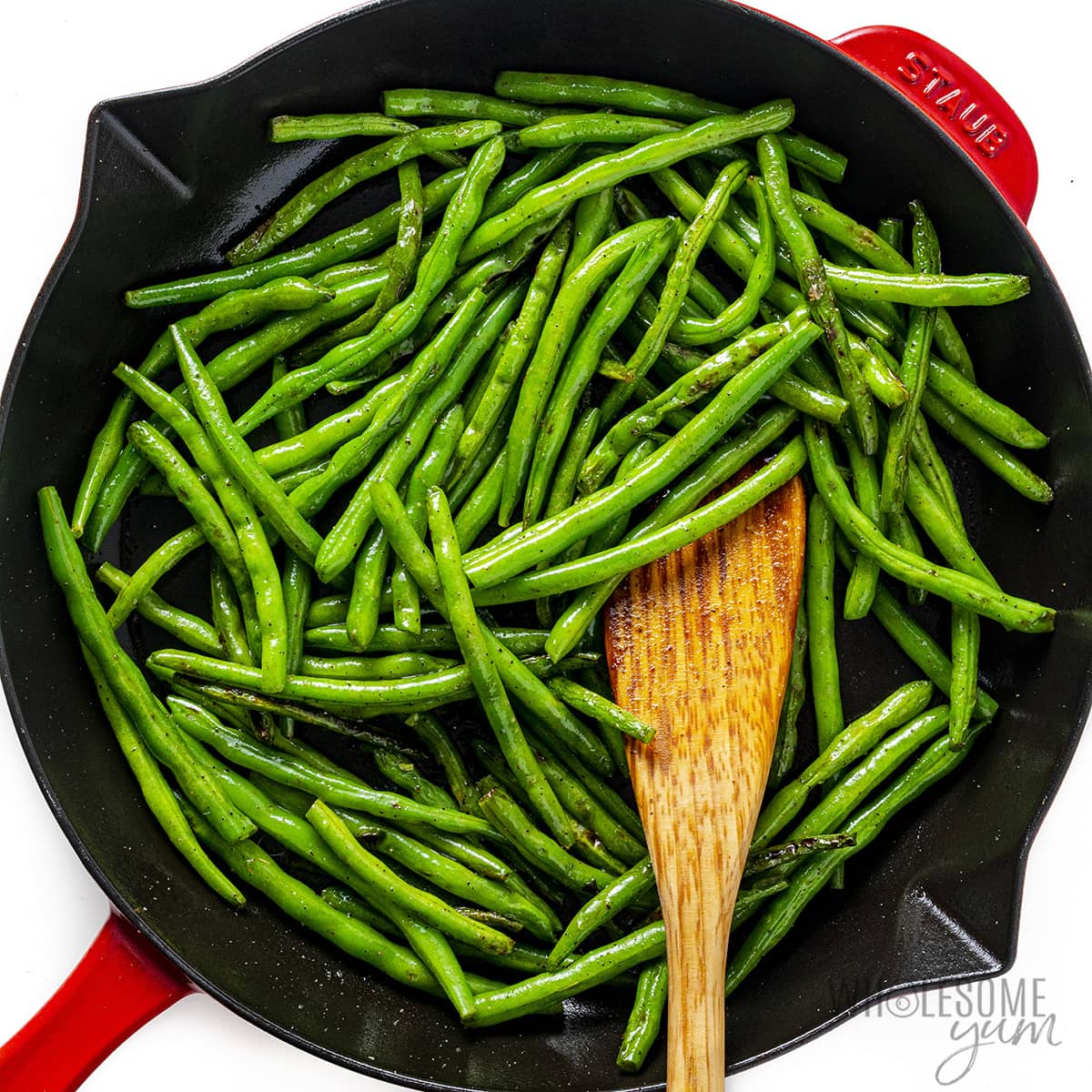 Use a wooden spoon to serve green beans in skillet.
