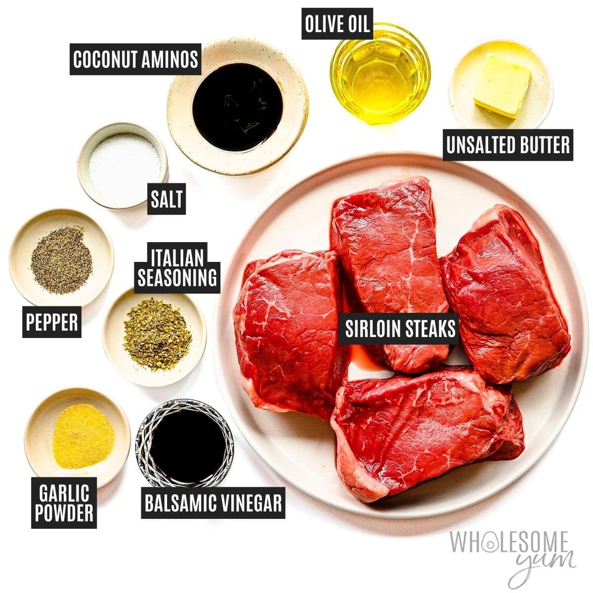 Steaks on a plate next to small bowls of oil, spices, and butter.