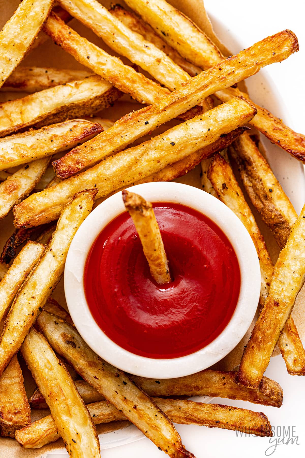 Air fryer french fries with one dunked in ketchup.