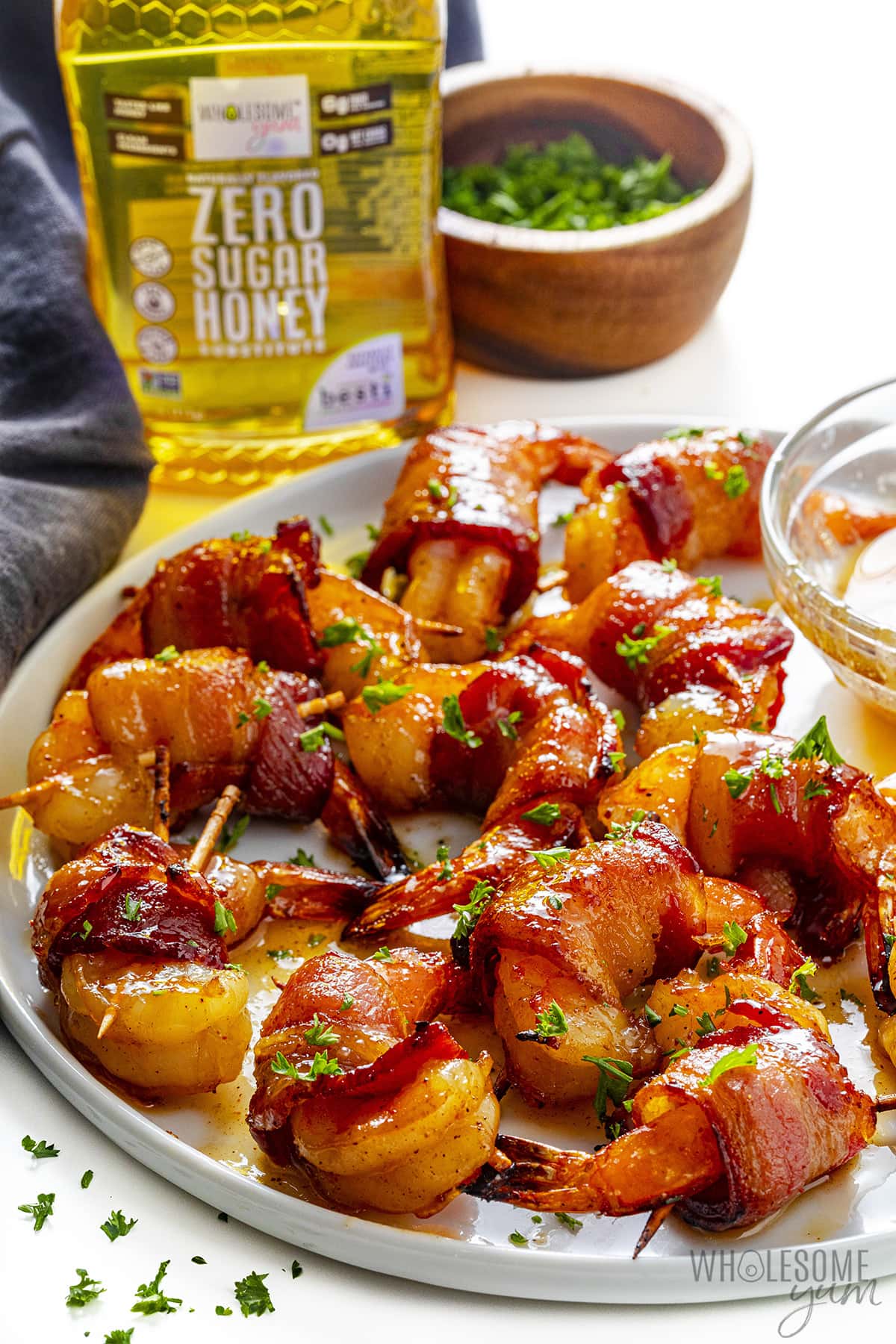 Shrimp wrapped in bacon on a plate next to sauce and zero sugar honey.