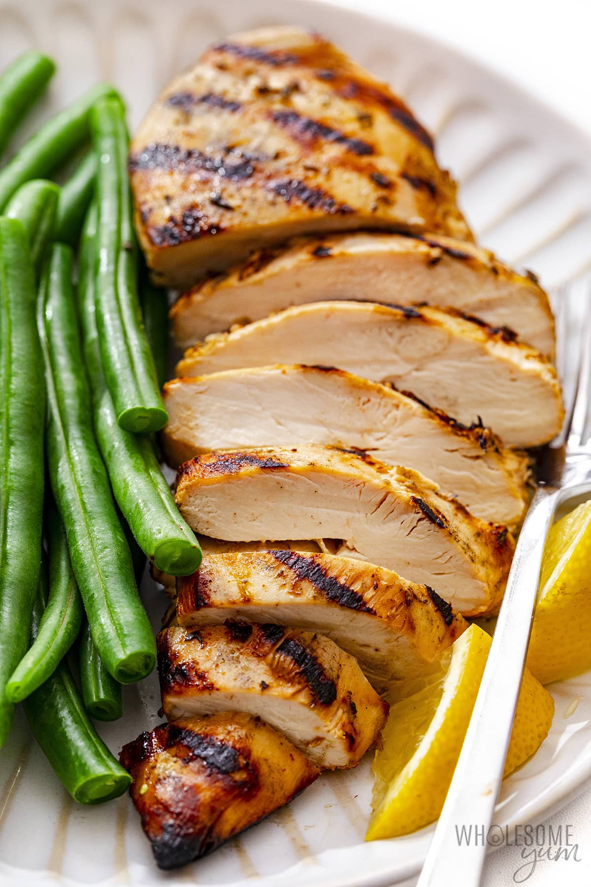Grilled chicken breast plated with green beans.
