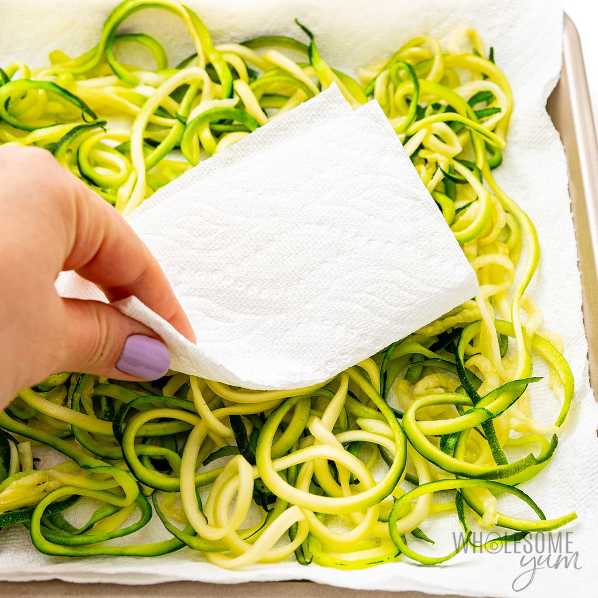 Patting zucchini noodles dry with paper towel.