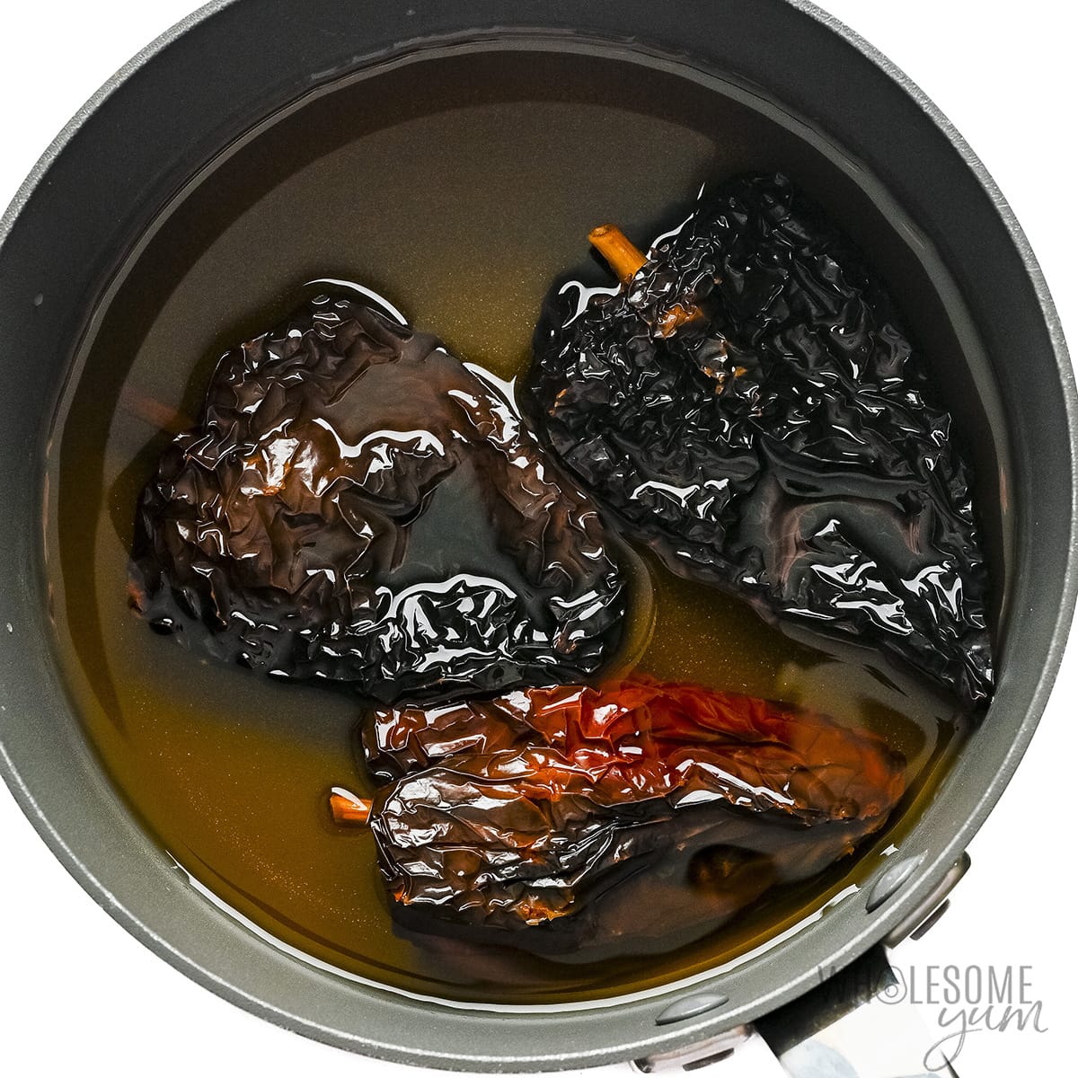 Ancho chiles soaking in a pot of water.