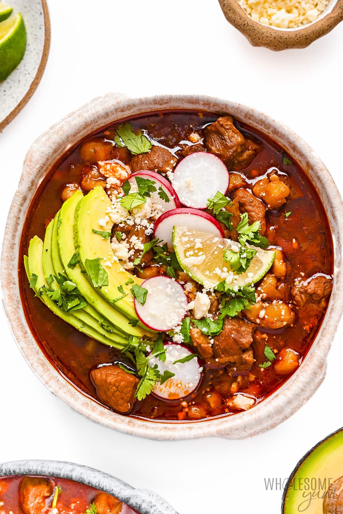 Pork pozole rojo in a bowl with toppings.