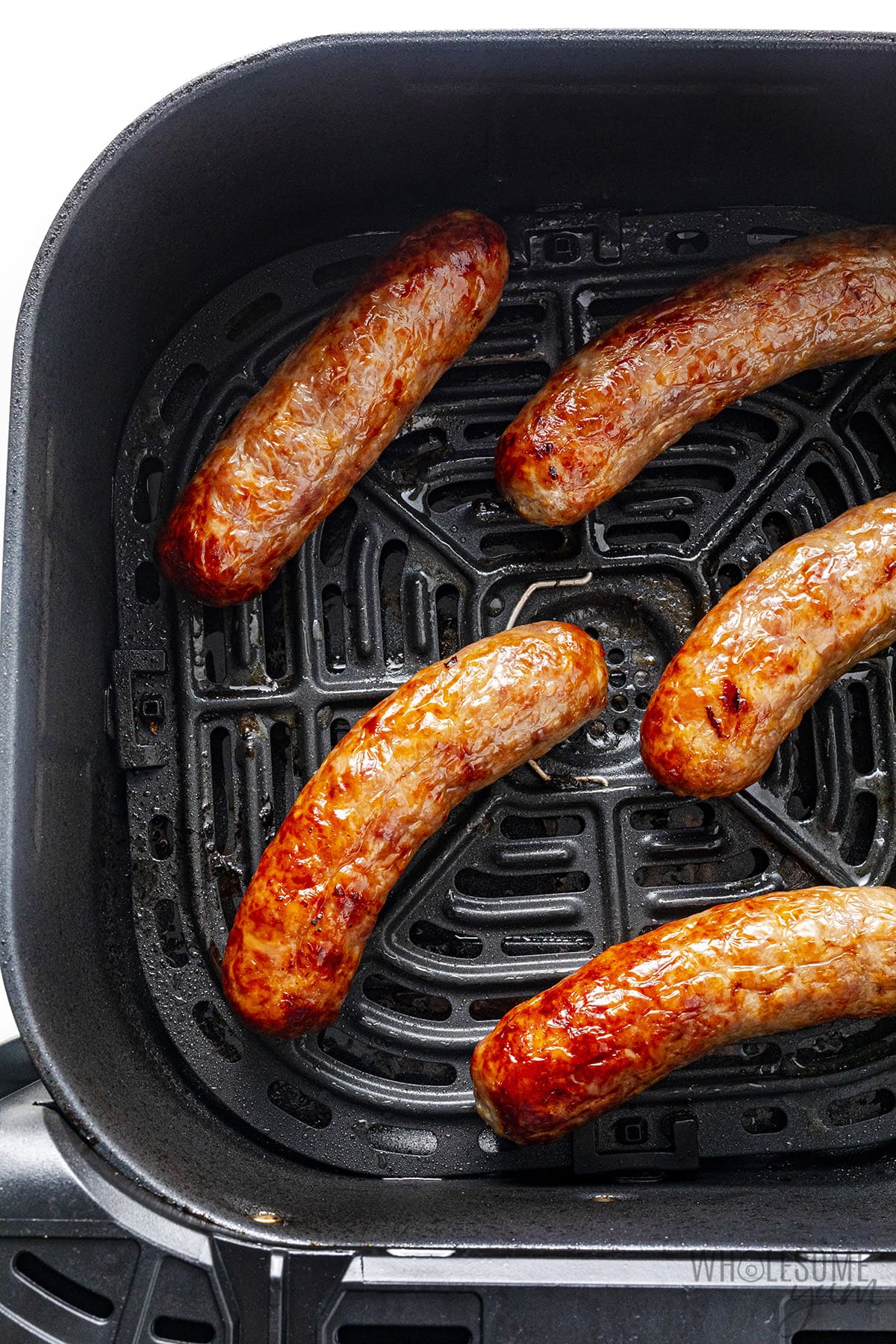 The air fryer brat is placed in the air fryer basket.