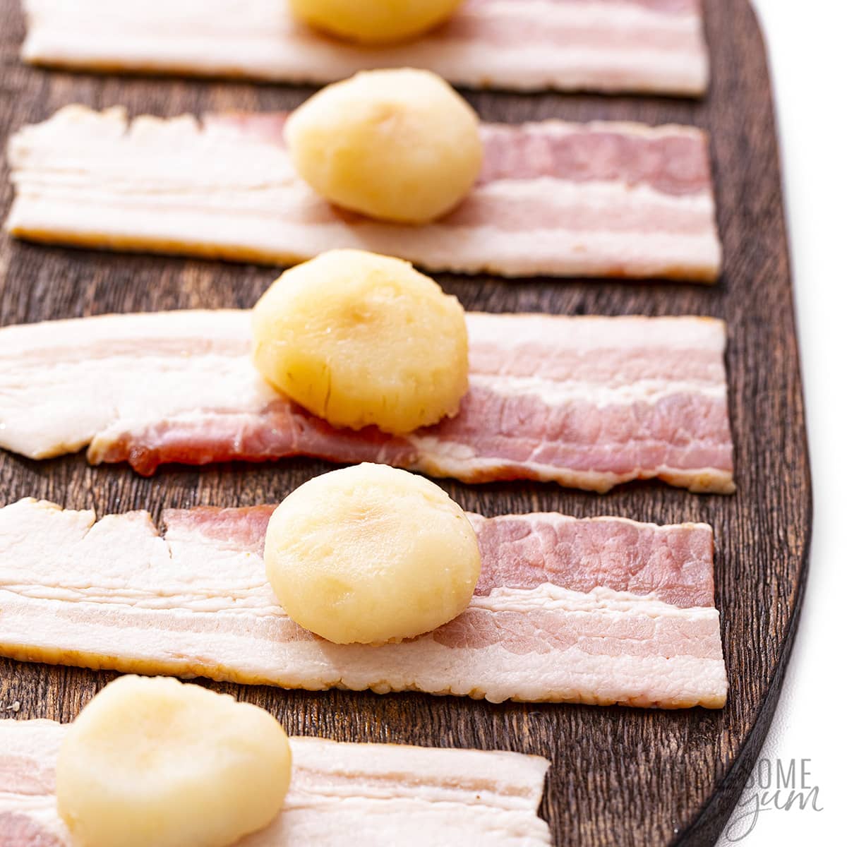 Water chestnuts in the center of raw bacon slices.