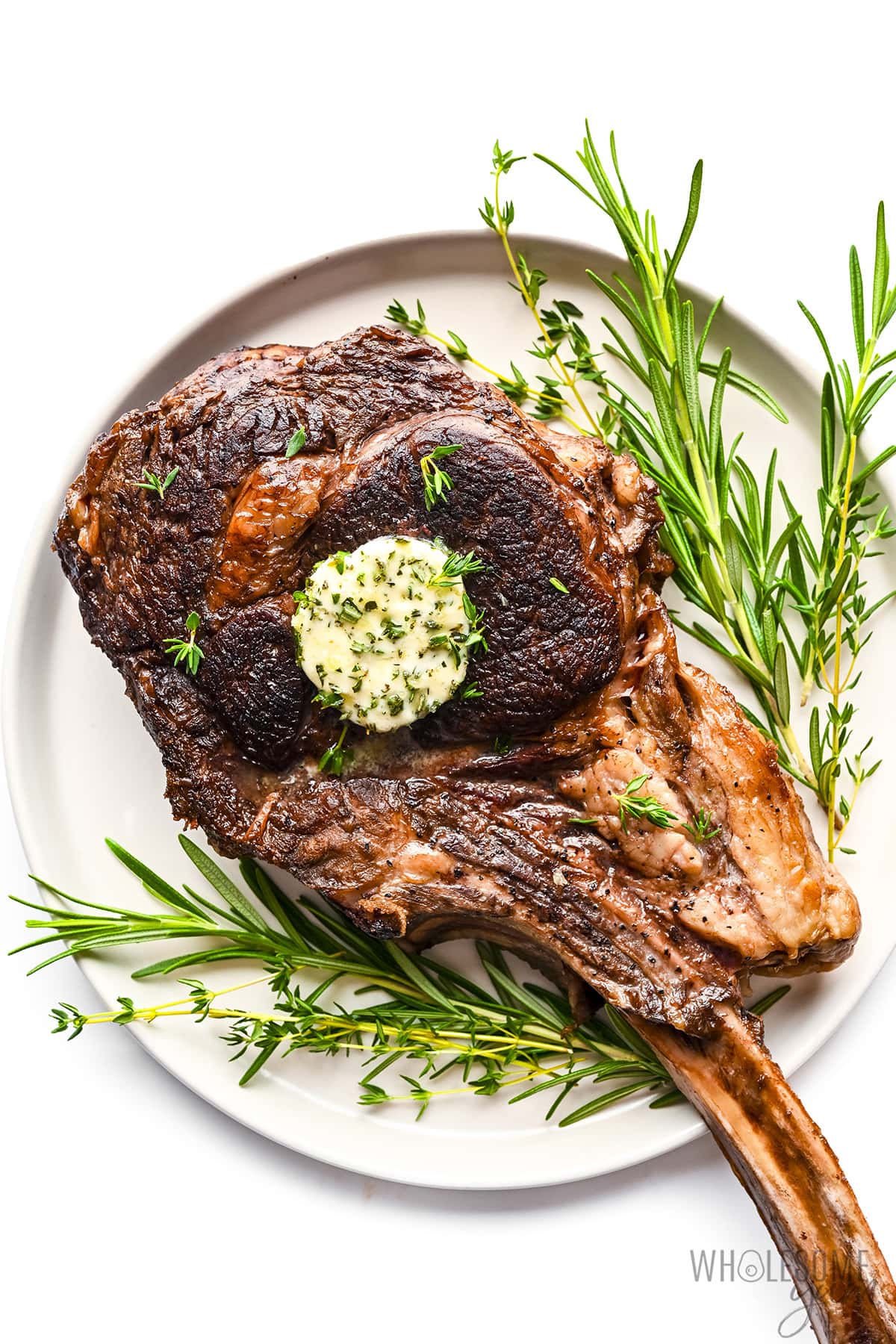 Tomahawk steak on a plate with herbs.
