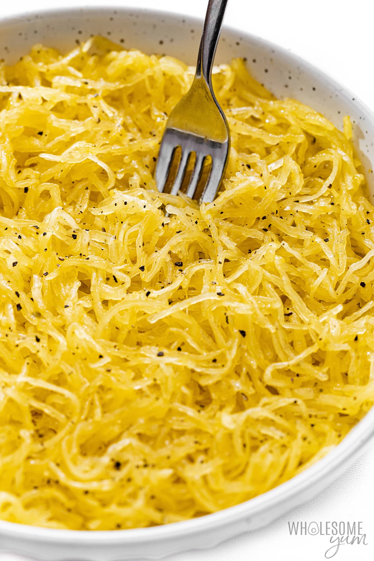 After cooking the spaghetti squash in the microwave, place the noodles in a bowl.