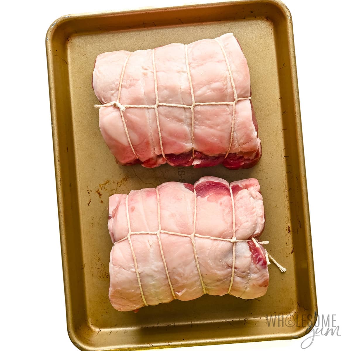 Pork sirloin roast tied with twine on a sheet pan.