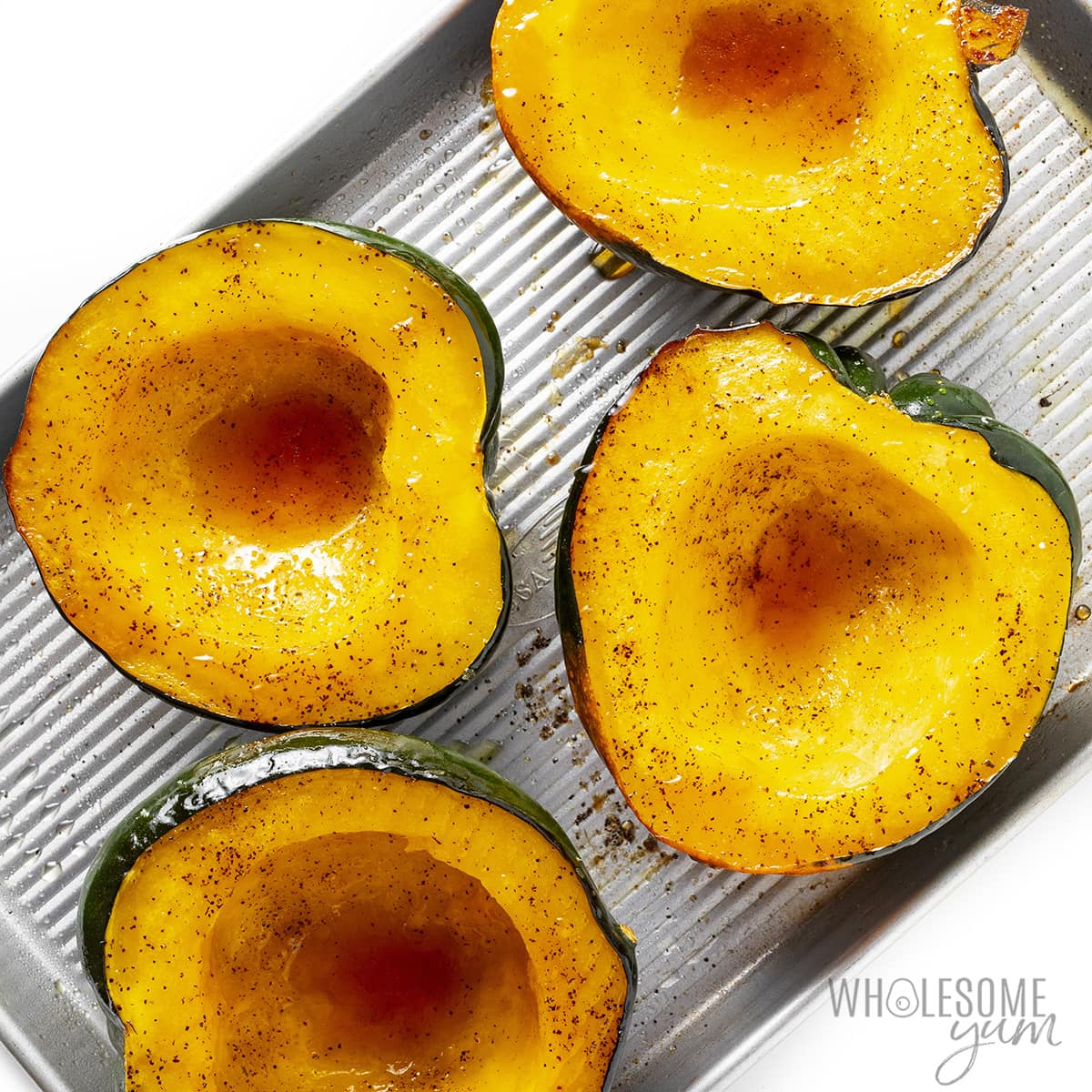 Squash drizzled with maple syrup and cut side up on a baking sheet.
