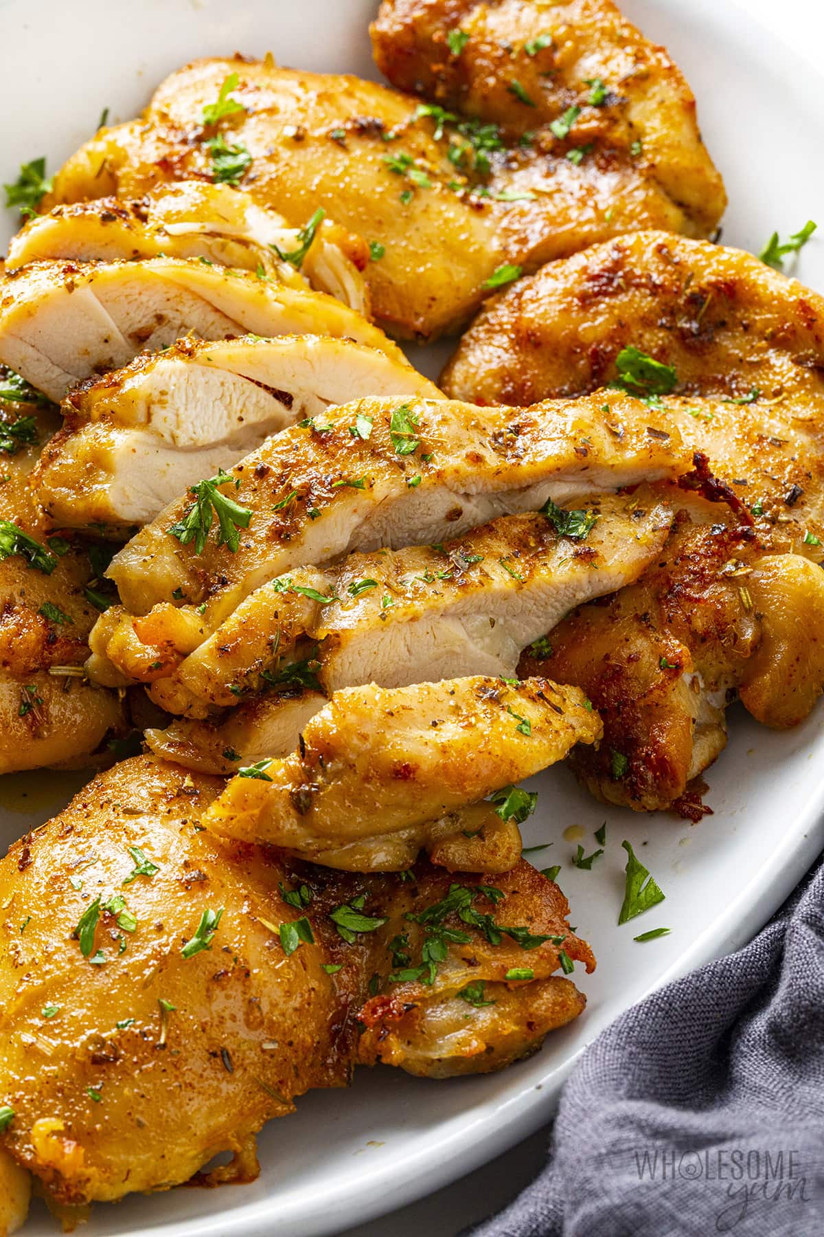 Sliced air fryer boneless chicken thighs on a serving platter.