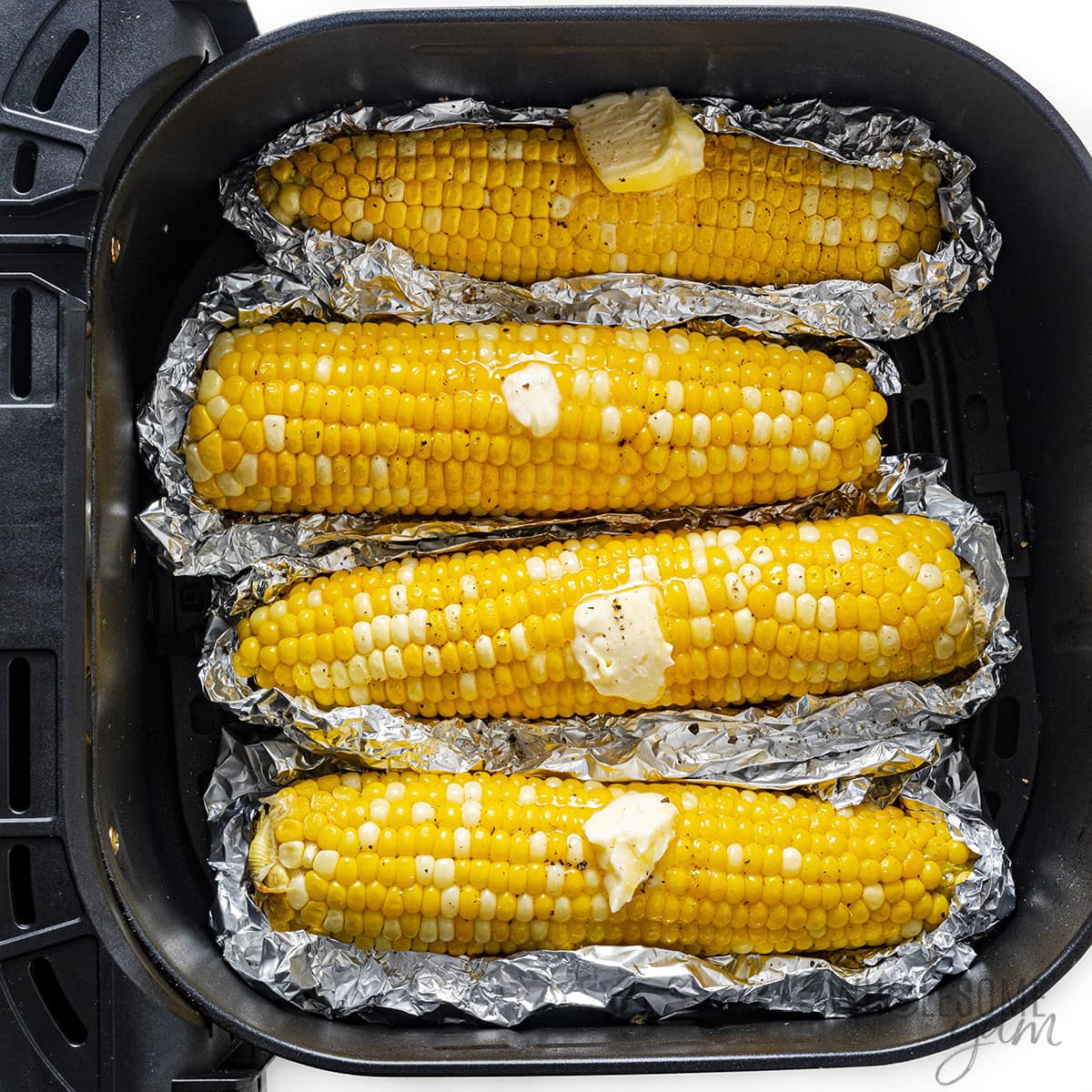 Corn in the air fryer, topped with butter.
