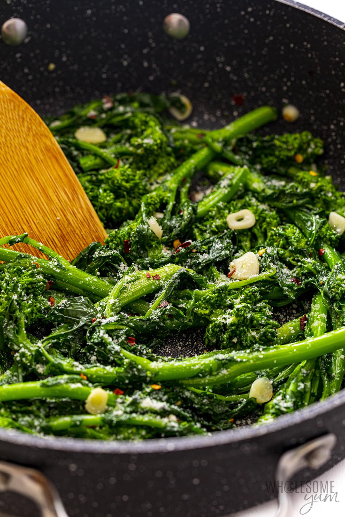 Broccoli rabe in a skillet with a wooden spoon.